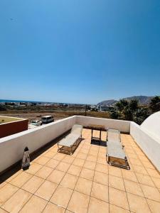 a patio with two benches and a table and chairs at Roxys sea view Santorini Monolithos in Santorini