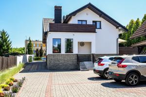 a white house with two cars parked in a driveway at Villa Laurent in Charzykowy