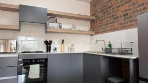 a kitchen with gray cabinets and a brick wall at CS Nest Modern Studio Athlone in Pietermaritzburg