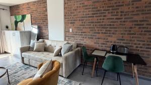 a living room with a couch and a brick wall at CS Nest Modern Studio Athlone in Pietermaritzburg