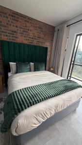 a large bed with a green headboard in a bedroom at CS Nest Modern Studio Athlone in Pietermaritzburg +3 photos