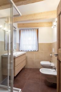 a bathroom with two sinks and a toilet and a window at Casa Chris by AMA Val di Fassa in Pozza di Fassa