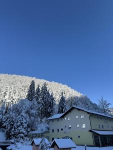 a building covered in snow with a mountain in the background at Divlje vode in Stojdraga