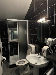a black tiled bathroom with a toilet and a sink at Divlje vode in Stojdraga