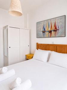 a bedroom with a white bed and a painting of sailboats at Andromeda Apartment in Polis Chrysochous
