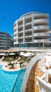 a swimming pool with chairs and a building at Hotel Premier & Suites - Premier Resort in Milano Marittima