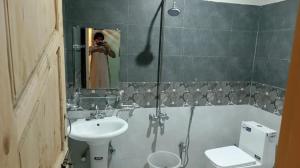 a woman taking a picture of a bathroom with a toilet and sink at Royal Palace in Naran