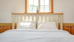 a bed with two white pillows and a window at Daebudo Sketch Pension in Ansan