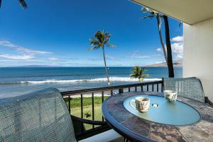 a table with two coffee cups on a balcony with the beach at SUGAR BEACH RESORT, #319 in Kihei