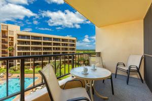 a balcony with a table and chairs and a pool at SUGAR BEACH RESORT #412 in Kihei