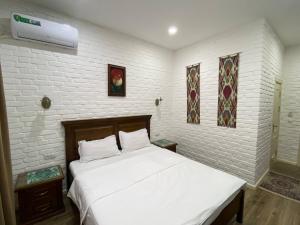 a bed in a room with a white brick wall at Orda Hotel in Yunusobod