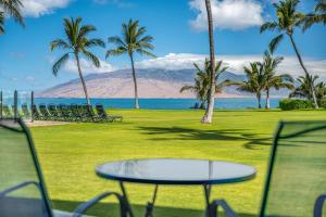 a table and chairs with a view of the ocean and mountains at KIHEI SURFSIDE #109 in Wailea