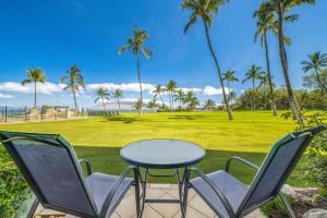 a patio with a table and chairs and palm trees at KIHEI SURFSIDE #109 in Wailea