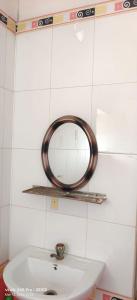 a mirror on a wall above a white sink at Mayurbhanj Stay Inn in Baripāda