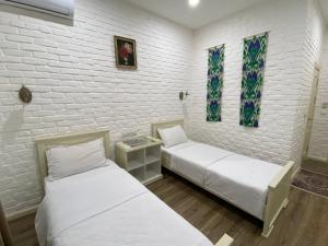 two beds in a room with white brick walls at Orda Hotel in Yunusobod +11 photos