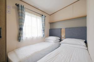 two beds in a small room with a window at Cockerham Sands Holiday Park in Cockerham +21 photos