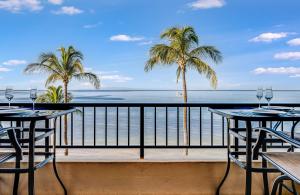 a balcony with two tables and palm trees and the ocean at SUGAR BEACH RESORT, #PH27 in Kihei