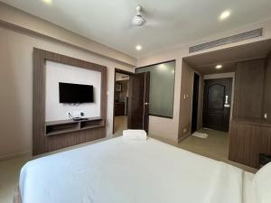 a bedroom with a large white bed and a flat screen tv at Shore Appartments in Udupi