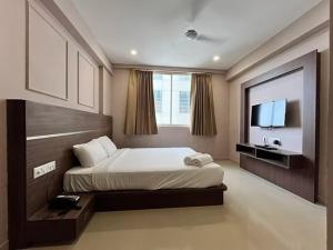 a bedroom with a bed and a television in it at Shore Appartments in Udupi