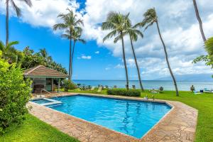 a pool with palm trees and the ocean in the background at Hale Mahina #B-405 in Honokowai