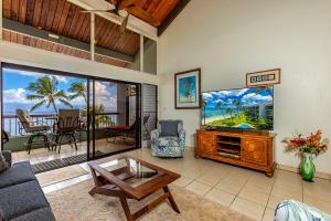 a living room with a tv and a couch and a table at Hale Mahina #B-405 in Honokowai +24 photos