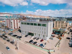 a large white building in a city with a parking lot at Zenn Hotel Erdenet in Erdenet
