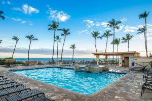 a swimming pool with palm trees and the ocean at SUGAR BEACH RESORT, #409 in Kihei