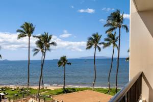 a view of the beach and palm trees from a balcony at SUGAR BEACH RESORT, #409 in Kihei
