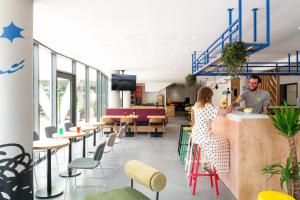 a man and a woman sitting at a bar in a restaurant at ibis Styles Angouleme Centre in Angoulême