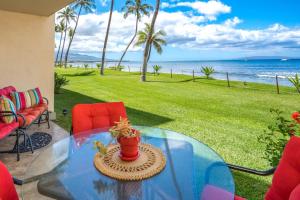 a glass table on a patio with a view of the ocean at SUGAR BEACH RESORT, #131 in Kihei