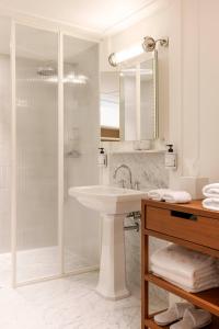 a white bathroom with a sink and a shower at Hotel Montaigne in Ostend
