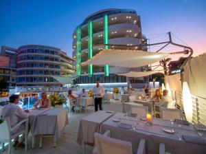 a group of people sitting at tables on a deck at Hotel Premier & Suites - Premier Resort in Milano Marittima