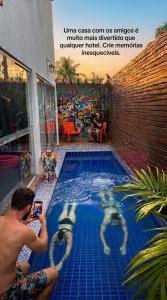 a man taking a picture of two people in a swimming pool at Hostel do Mago in Pipa