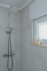 a bathroom with a shower with a shower head at Kalumi Aparthotels - Japandi-Style Apartments with Terrace, Pergola, and Portuguese BBQ in Vila Nova de Milfontes +43 photos