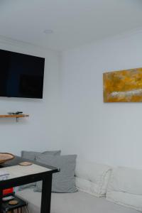 a living room with a couch and a tv on a wall at Kalumi Aparthotels - Japandi-Style Apartments with Terrace, Pergola, and Portuguese BBQ in Vila Nova de Milfontes