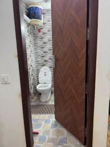 a bathroom with a toilet and a wooden door at Hotel Vasundhara Villa - Greater Kailash in New Delhi +23 photos