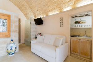 a living room with a white couch and a tv at Corte Donato Grasso Relax - Salento Selection in Alessano