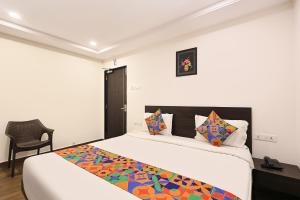 a bedroom with a large bed and a chair at FabHotel Excella Vizag in Visakhapatnam