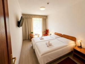 a bedroom with a large white bed in a room at PSZ Hotel Beach Földvár in Balatonföldvár