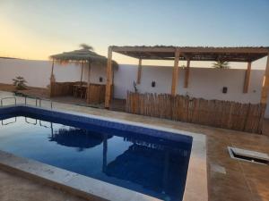 a swimming pool in front of a house with an umbrella at Villa jenni in Temlale