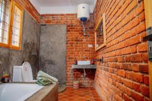 a bathroom with a brick wall and a bath tub at Tranquil Hillhouse in Nkoanrua +92 photos