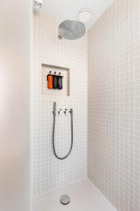 a shower in a bathroom with white tiles at Duinhotel Tien Torens in Zoutelande +91 photos
