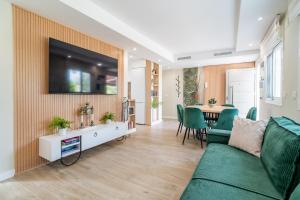a living room with a couch and a television on a wall at Cubo's Violeta Rural House in Coín