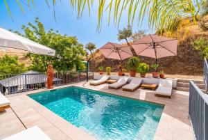 a swimming pool with umbrellas and lounge chairs next to a swimming poolvisor at Cubo's Violeta Rural House in Coín