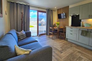 a living room with a blue couch and a kitchen at Chata in Stornoway