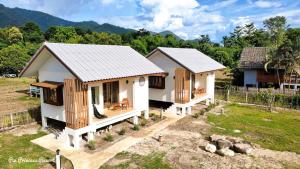 two small white houses with wooden windows in a field at Pai Princess Resort in Pai