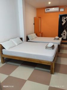 two twin beds in a room with an orange wall at Danshika Temple Residency in Aduturai