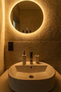 a bathroom with a sink with a round mirror at 313 apartments in Užpelkiai +34 photos