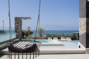 a swinging chair in front of a swimming pool at Moonlight Villas Calypso - Sleek Coastal Living by etouri in Koutsourás +104 photos