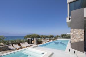 a swimming pool with chairs and the ocean in the background at Moonlight Villas Calypso - Sleek Coastal Living by etouri in Koutsourás